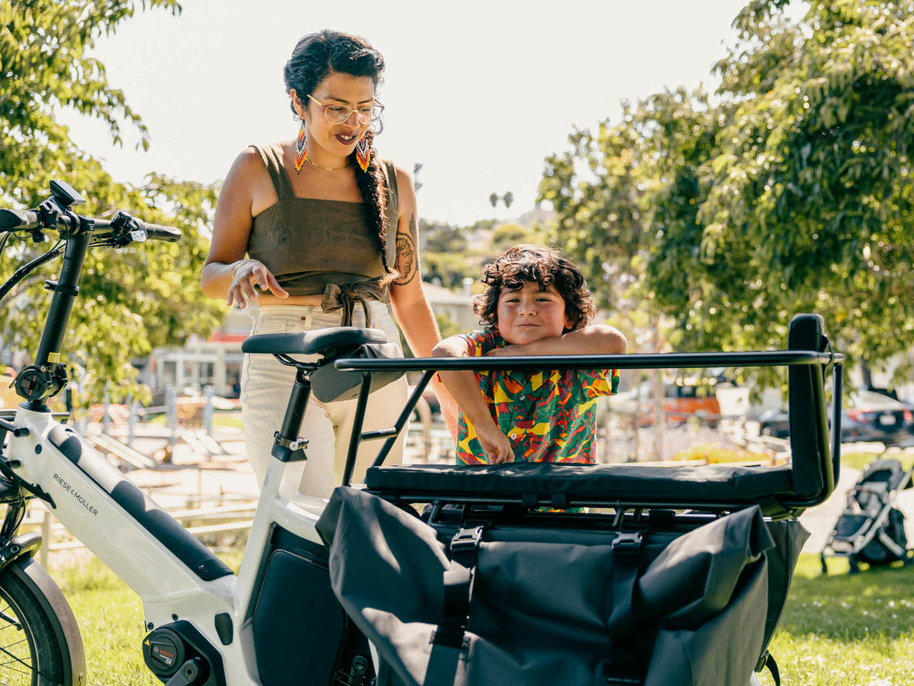 A mother and son enjoy the shade next to their long tail electric cargo bike