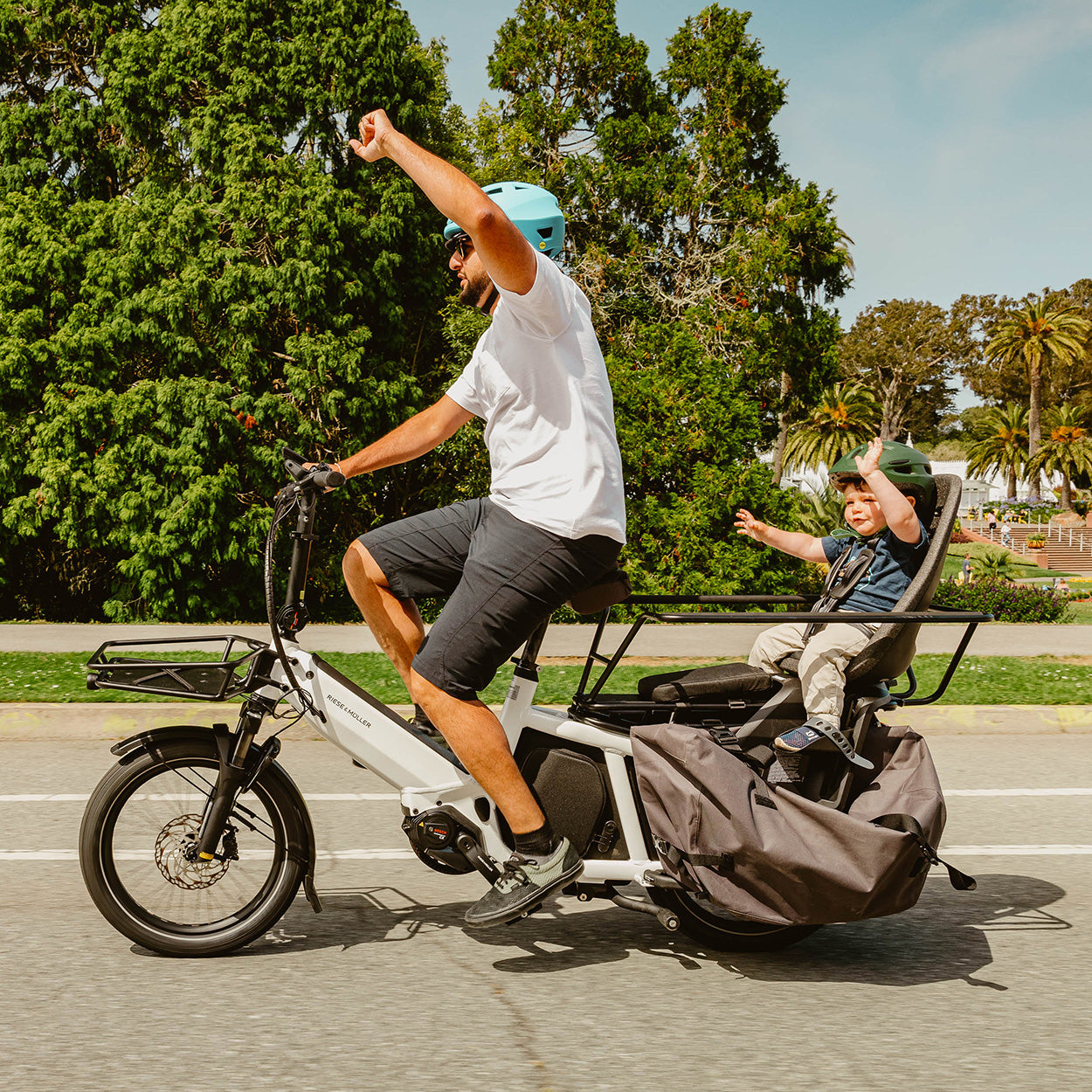 Father & son riding a cargo bike through the park